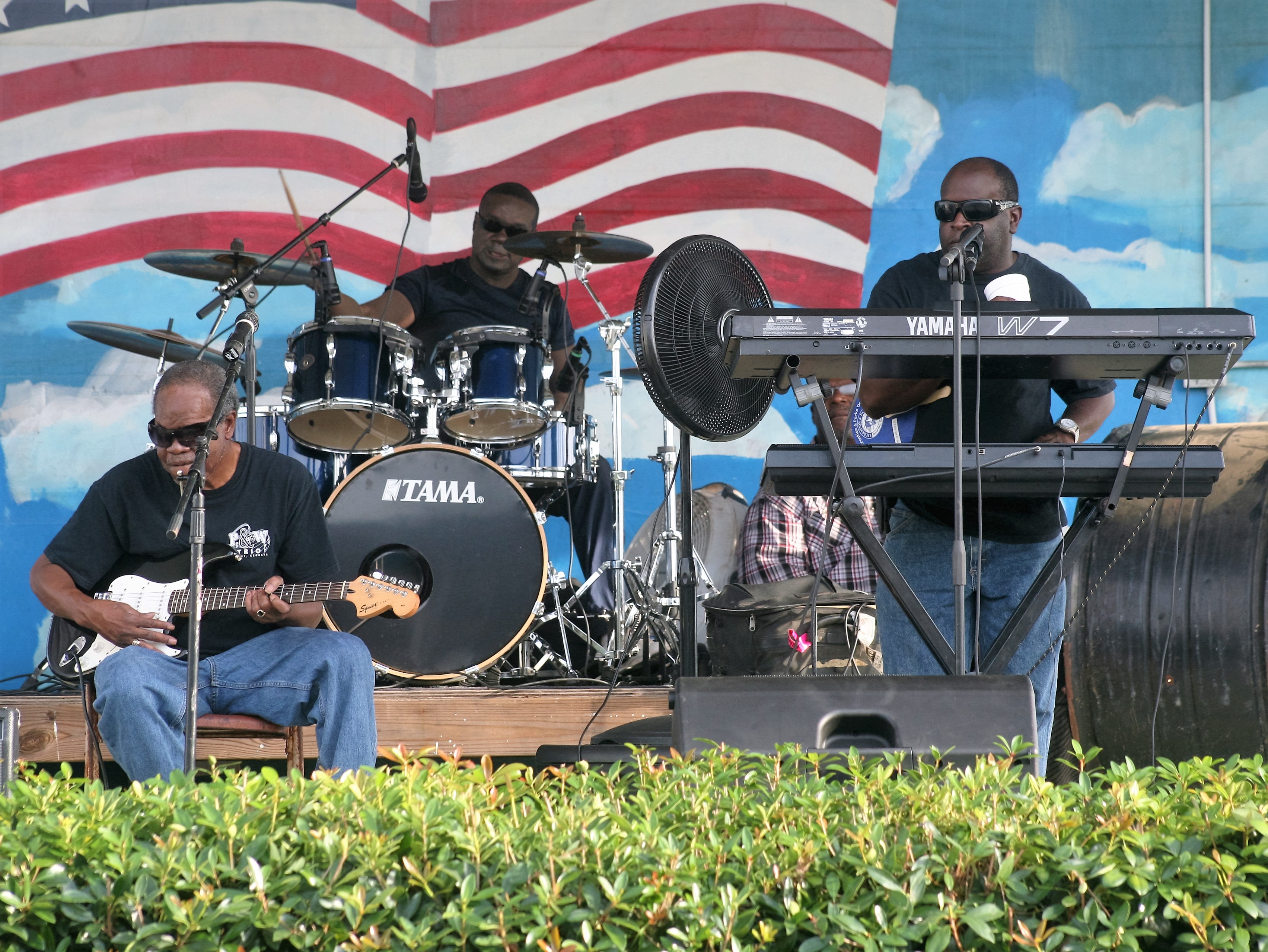 M&M Blind Boys Band performing live on stage with guitar, drums, and keyboard